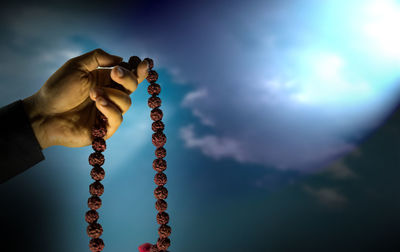 Low angle view of man holding rope against sky