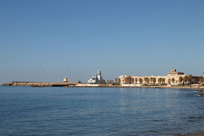 Sea by buildings against clear blue sky