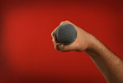 Cropped image of singer holding microphone against red background