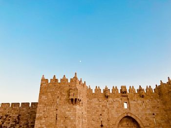 Low angle view of fort against clear blue sky