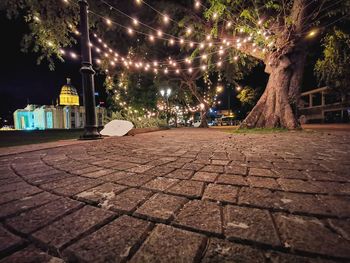 View of illuminated street by building at night