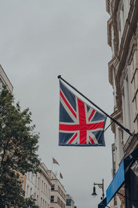 Low angle view of flag amidst buildings in city against sky