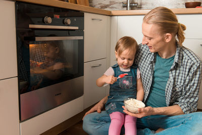 Father and kid waiting for freshly baked buns bread, cinnabons or pastry near the oven happy time