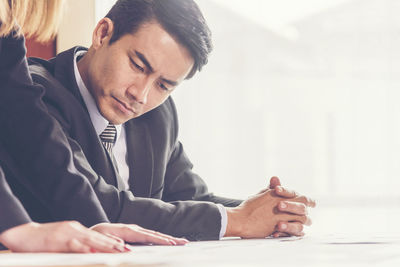 Midsection of businesswoman explaining to businessman in office