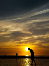 Silhouette people by sea against sky during sunset