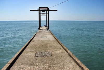 Pier over sea against clear blue sky