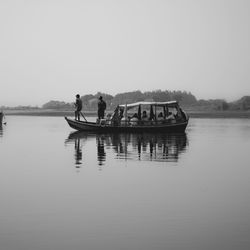 People on rowboat in lake against clear sky