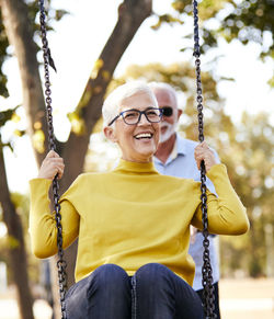 Portrait of smiling woman sitting on swing at playground