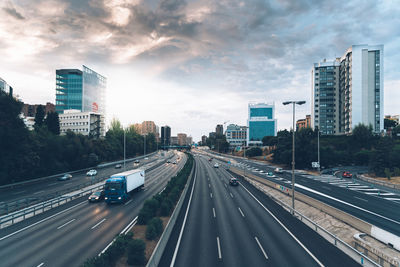 Vehicles on highway in city against sky