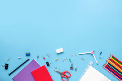 High angle view of school supplies over blue background