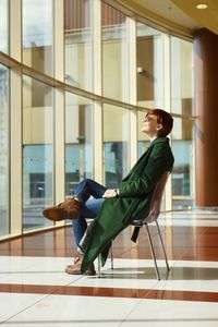 Side view of a young woman sitting by window