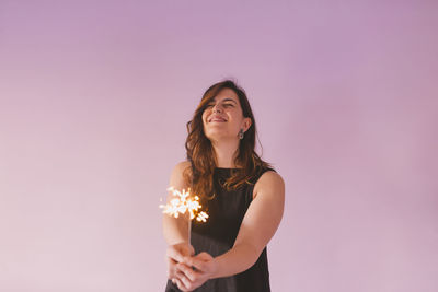 Beautiful young woman standing against pink background