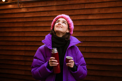 Young happy. a woman is drinking hot tea while holding a thermos on a winter