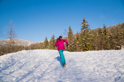 Rear view of woman on snow covered land against sky