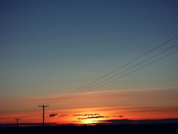 Silhouette of electricity pylon at sunset