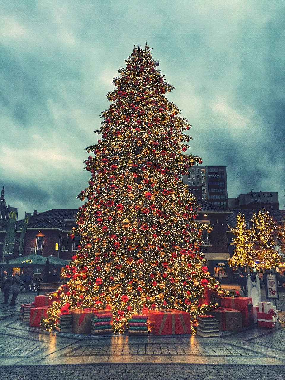 illuminated, building exterior, architecture, sky, built structure, celebration, night, christmas, christmas tree, christmas decoration, decoration, city, cloud - sky, low angle view, tree, lighting equipment, tradition, christmas lights, cloudy, outdoors