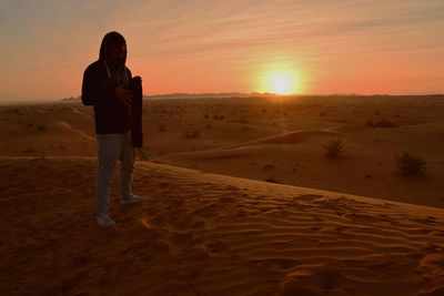 Man standing on desert during sunset