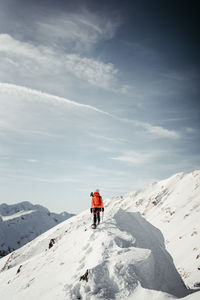 People skiing on snow covered mountain against sky