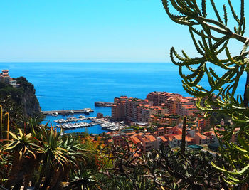 Scenic view of sea by buildings against clear blue sky