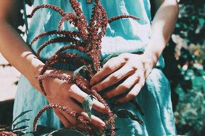 Midsection of woman holding plant during sunny day