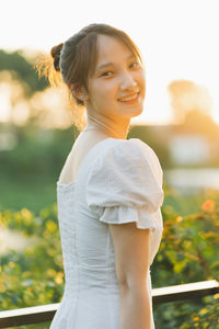 Portrait of young woman standing against trees