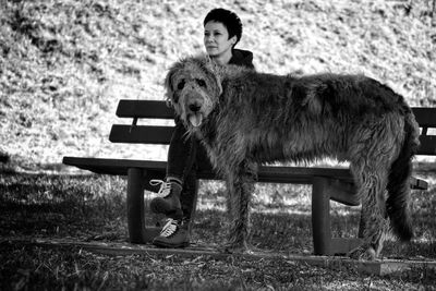 Woman sitting on bench with irish wolfhound at field