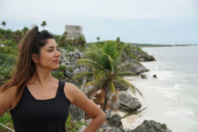 Young woman standing on rock at beach