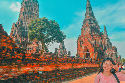 Portrait of smiling young woman standing against built structure