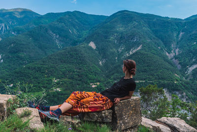 Rear view of woman sitting on mountain