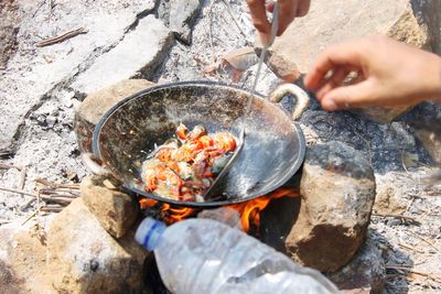 Midsection of man preparing food on rock