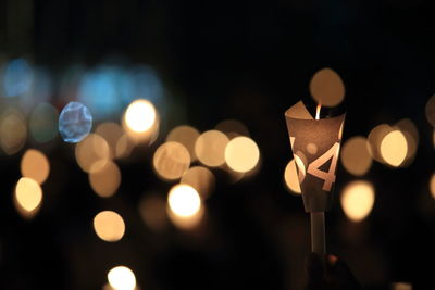 Close-up of illuminated candle with number on paper at night