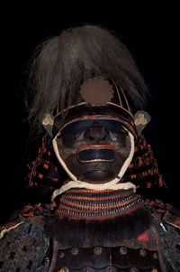 Close-up portrait of man wearing mask against black background