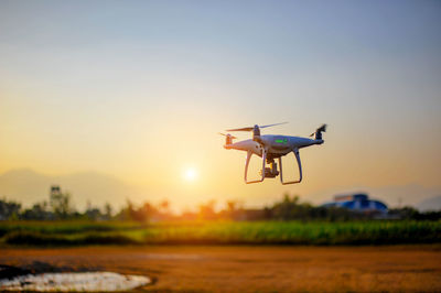 Drone flying against sky during sunset