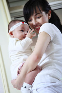 Low angle view of mother holding toddler daughter at home