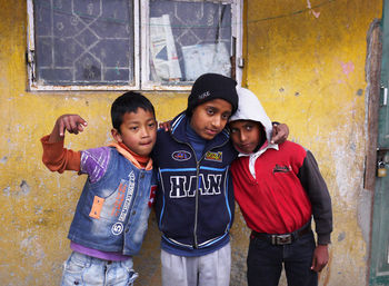 Portrait of friends standing against the wall