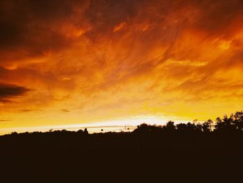 Silhouette landscape against dramatic sky during sunset