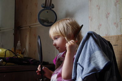 Cute girl dressing hair up looking at mirror at home