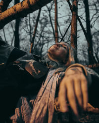 Woman lying on tree in forest