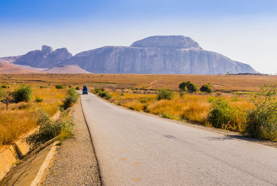 Road leading towards mountains against sky