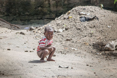 Boy crouching on road in village