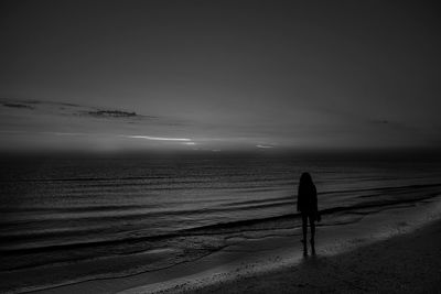 Rear view of man on beach against sky