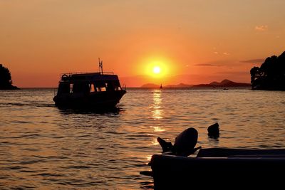 Silhouette boat in sea against sky during sunset