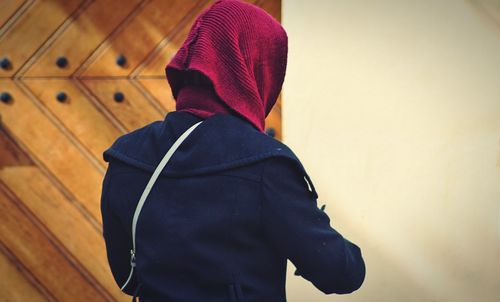 Rear view of woman wearing headscarf standing against wall