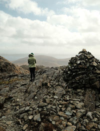 Rear view of man walking on rock against sky