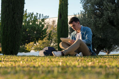 Side view of young man sitting on book