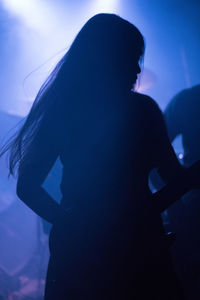 Silhouette woman playing guitar at music concert