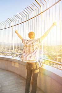 Rear view of man standing on bridge against sky