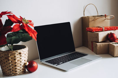 Blank display screen laptop computer with poinsettias christmas flower and gift boxes on white