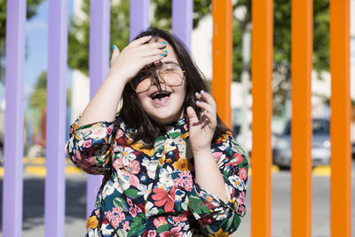 Portrait of young woman standing by railing