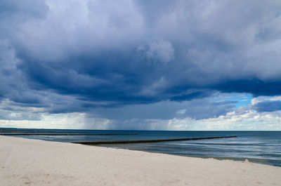 View of calm beach against cloudy sky